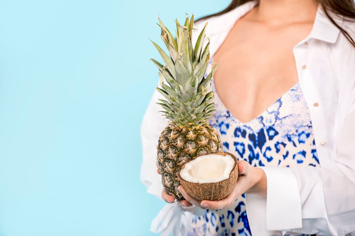 Smiling pregnant woman eating a bowl of pineapple