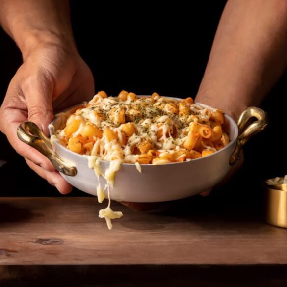 How to Make Darius Cooks Mac And Cheese Hands serving creamy baked Darius Cooks Mac And Cheese topped with herbs in a white bowl with golden handles.
