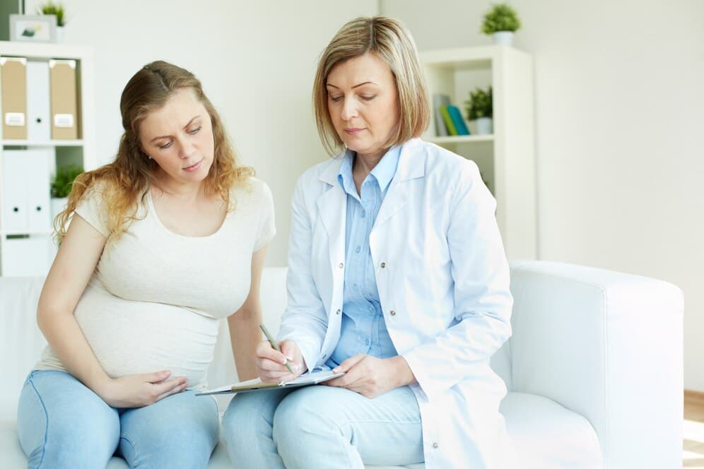Pregnant woman in third trimester speaking with a midwife in a medical setting